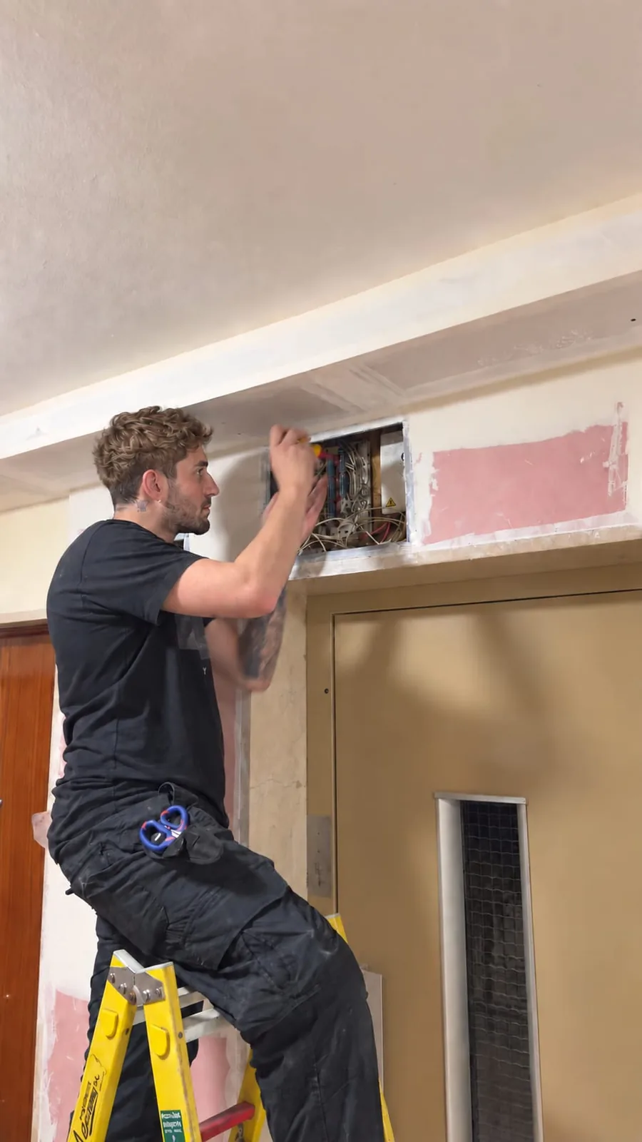 Técnico de MF Telecomunicaciones renovando la vertical de fibra óptica junto al ascensor de un edificio residencial en Madrid