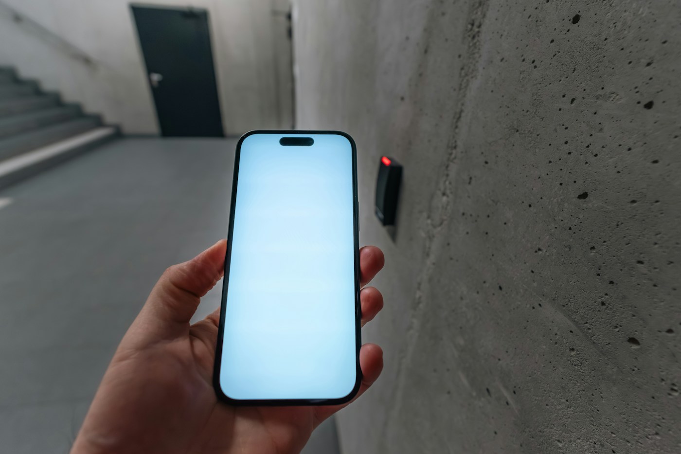 Persona utilizando un móvil ante un lector de control de acceso